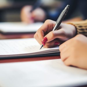 Close-up shot of a student's hand holding a pencil and writing i